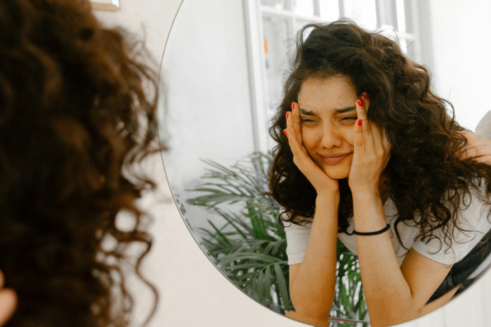 a girl watching in mirror with self doubt